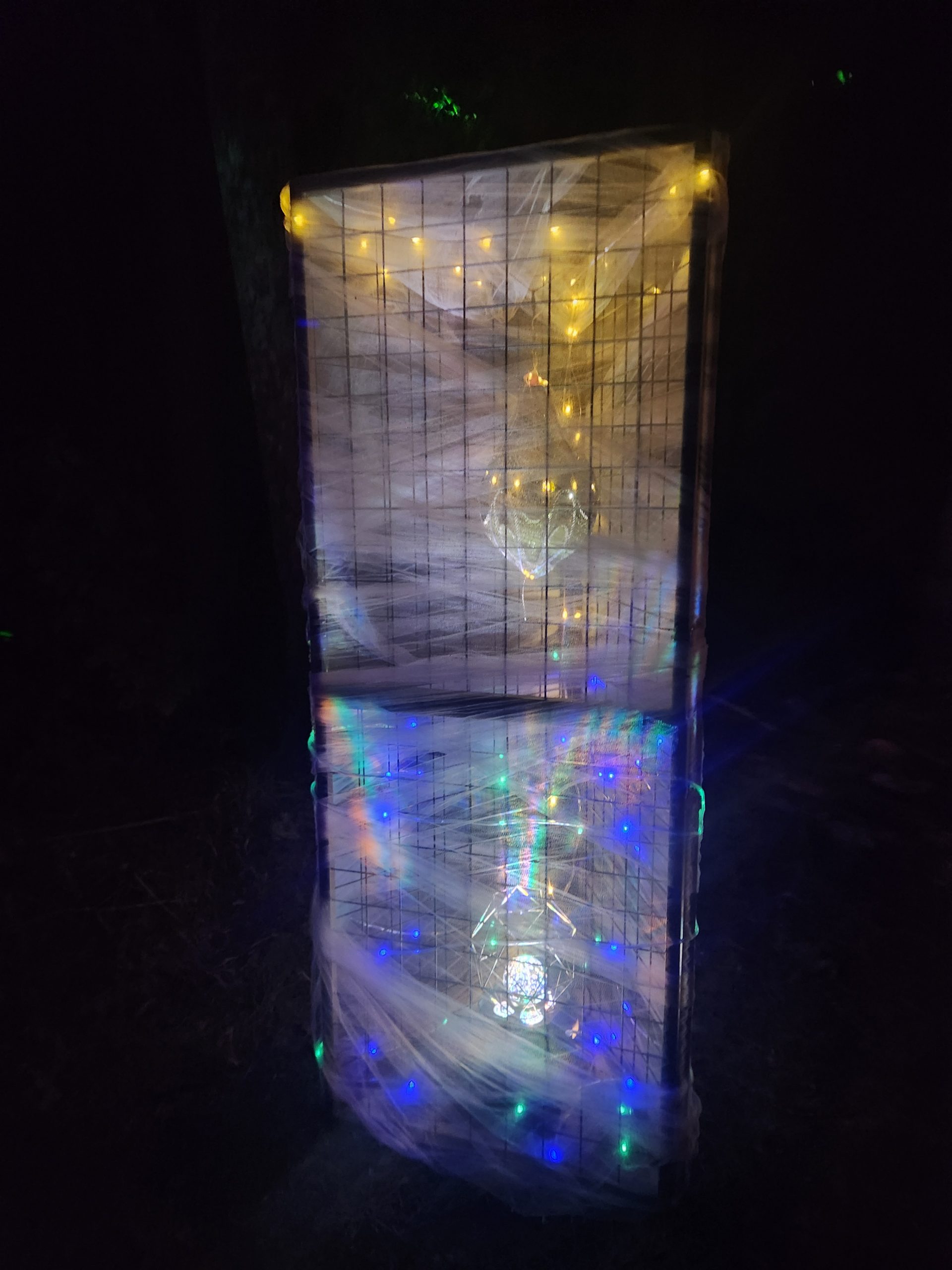 Close view inside a lattice panel showing gold crystal geometry and prismatic colored light through translucent fabric